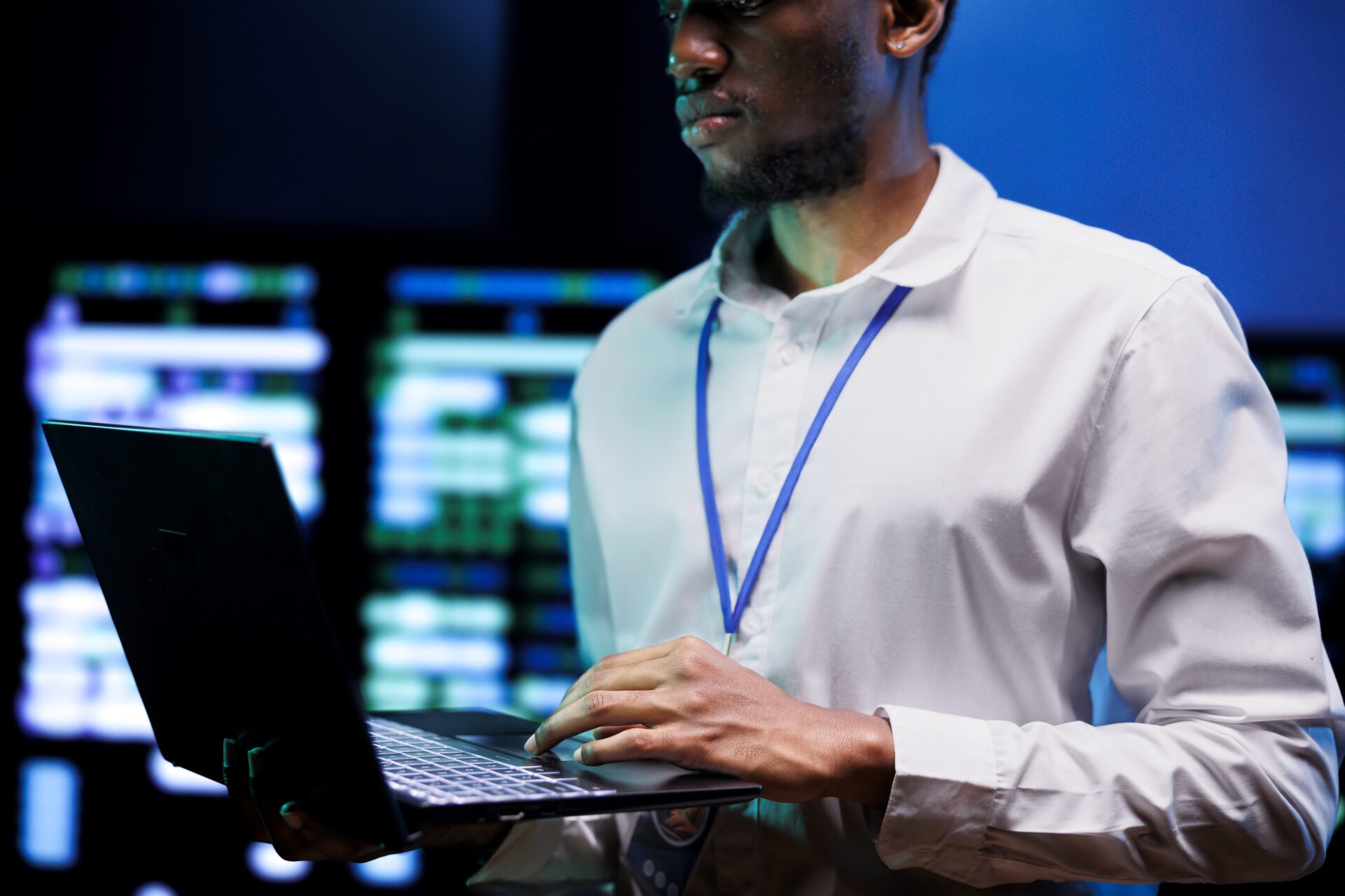 Manager using laptop to survey high tech supercomputers providing vast computing resources and storage. Server farm enabling artificial intelligence to process massive datasets for training